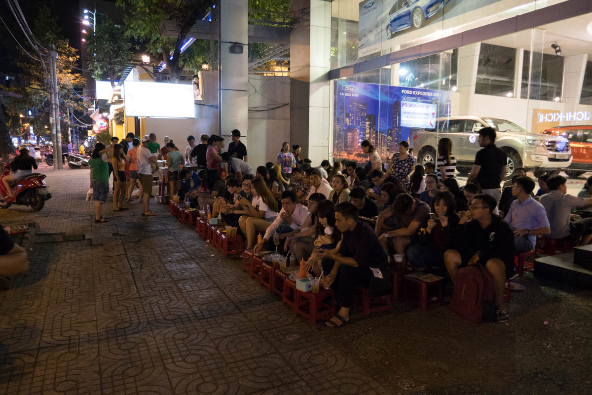 people eating at the sidewalk on the saigon street food tour